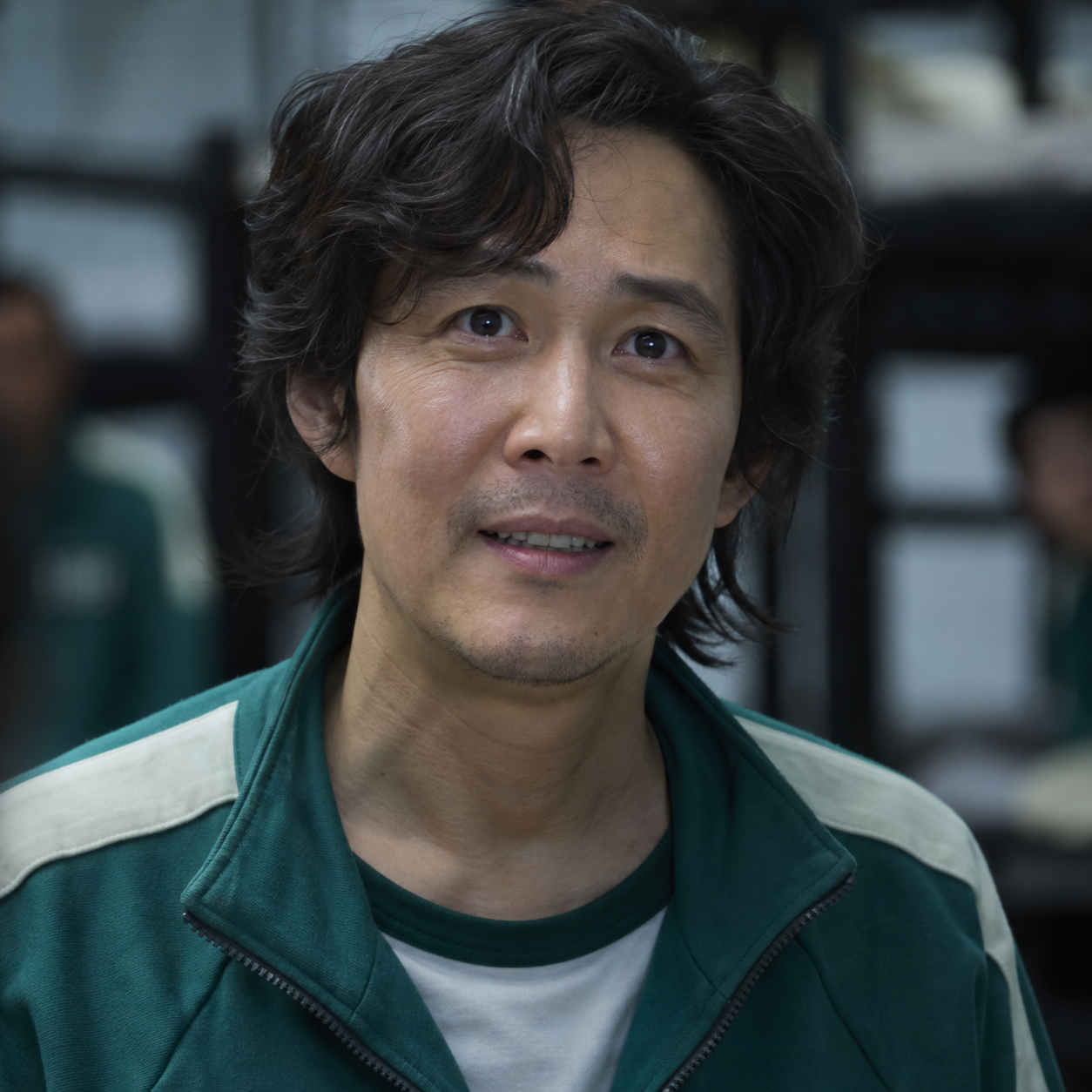 Lee Jung-jae as Seong Gi-hun, wearing a green tracksuit in a dormitory.